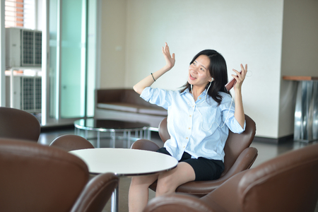 Asian business woman listening to music media in loungeの写真素材