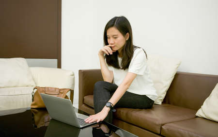 Asian business woman thinking in front of laptop at nightの写真素材