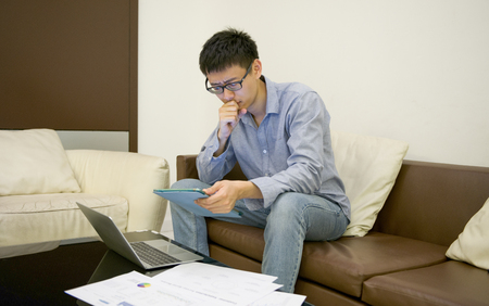 Asian businessman thinking in front of laptop at nightの写真素材