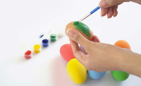 Hand painting colorful easter eggs on white background. Food decoration on holiday. People lifestyle.の写真素材