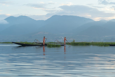 Burmese fisherman casting or throwing a net for catching freshwater fish in Unle lake, natural river in Asia in Myanmar. People lifestyle.の写真素材