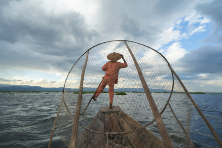 Burmese fisherman casting or throwing a net for catching freshwater fish in Unle lake, natural river in Asia in Myanmar. People lifestyle.の写真素材