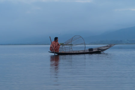 Burmese fisherman casting or throwing a net for catching freshwater fish in Unle lake, natural river in Asia in Myanmar. People lifestyle.の写真素材