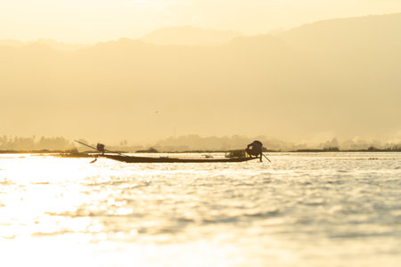 Burmese fisherman casting or throwing a net for catching freshwater fish in Unle lake, natural river in Asia in Myanmar. People lifestyle.の写真素材