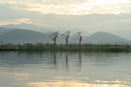 Burmese fisherman casting or throwing a net for catching freshwater fish in Unle lake, natural river in Asia in Myanmar. People lifestyle.の写真素材