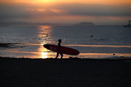 Surfer silhouette at dawn. Sunrise beach background.