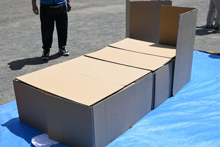 Disaster prevention drill. Assembling a cardboard bed for evacuation shelters. The floor of the evacuation shelter is hard and cold, so this bed allows get a good night's sleep.の写真素材