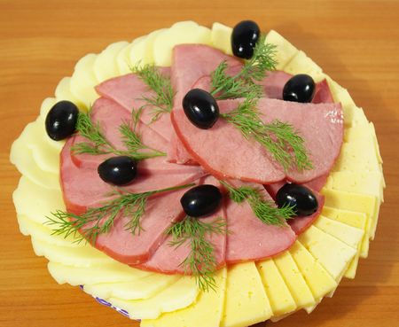 Ham, cheese, olives cut on a round plateの写真素材