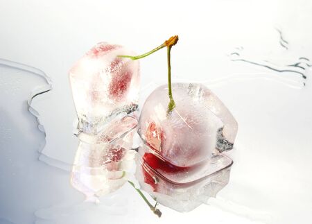 Two frozen cherries on white glass surfaceの写真素材