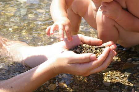 Human hands and sea stones. The daddy and his daughterの写真素材