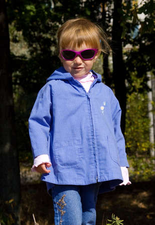 Cute little girl with sunglasses in the woodの写真素材