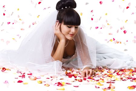 Beautiful bride in a white dress with rose petals. Studio shotの写真素材