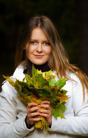 Portrait of a beautiful  smiling  young woman with maple leafsの写真素材