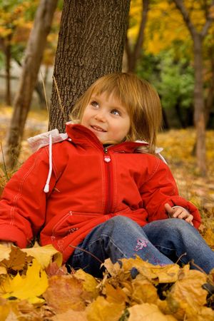 Cute little caucasian girl sit near the treeの写真素材
