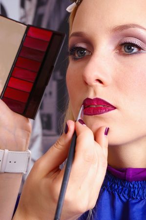 Makeup artist tracing red lipstick on the lips of a girlの写真素材