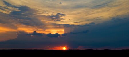 Sunset. The sun shining through low cloudの写真素材