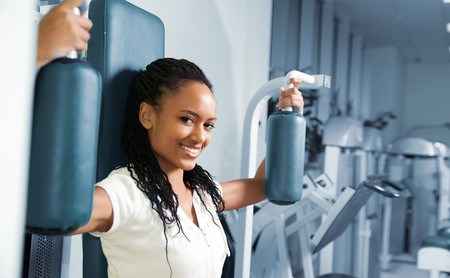A young woman in a gym with a confident smile