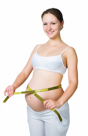 Beautiful pregnant woman measures her stomachの写真素材