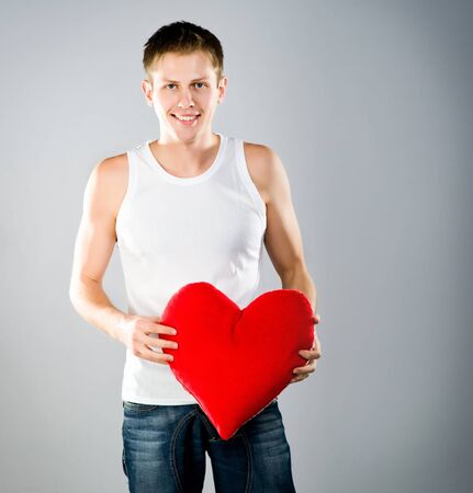 Cute young menl with a red heart. Studio shotの写真素材