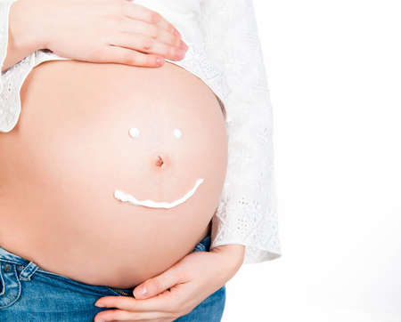 Beautiful pregnant young female with cosmetic cream on bellyの写真素材