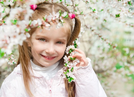 The beautiful little girl with bush blossoming treeの写真素材