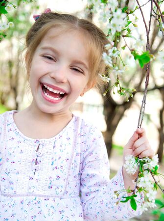 The beautiful little girl with bush blossoming treeの写真素材