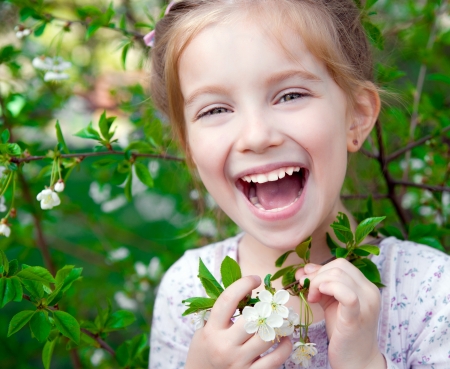 The beautiful little girl with bush blossoming treeの写真素材