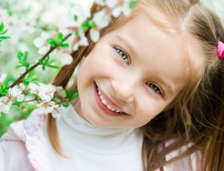 The beautiful little girl with bush blossoming treeの写真素材