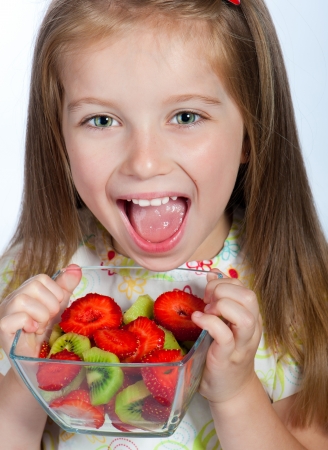 Cute little girl  with the  fruit salad on a white backgroundの写真素材