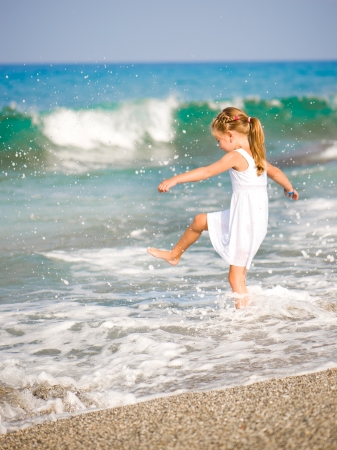 Adorable little girl make a splash on tropical beach vacationの写真素材