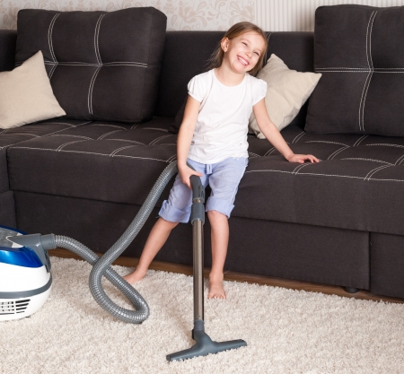 smiling little girl cleaning the room - using vacuum cleaneの写真素材