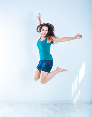 Beautiful jumping girl in a bright roomの写真素材