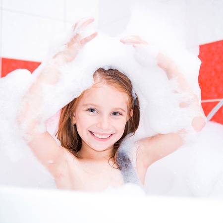 Small pretty girl is taking a bath with a foamの写真素材