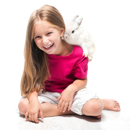 happy little girl in a pink T-shirt with a small white rabbitの写真素材