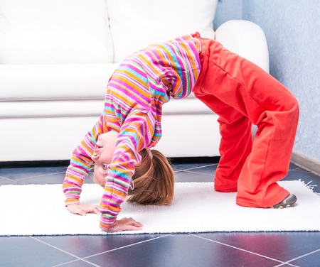 happy little girl playing sports at home in front of a white sofaの写真素材