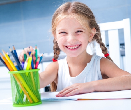 cute little girl drawing with pencils at home in the albumの写真素材