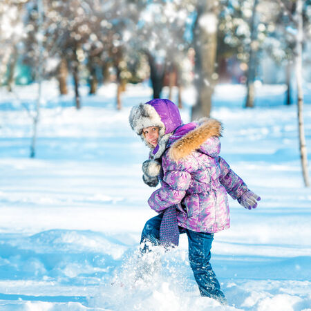 little girl playing with snow in the forestの写真素材