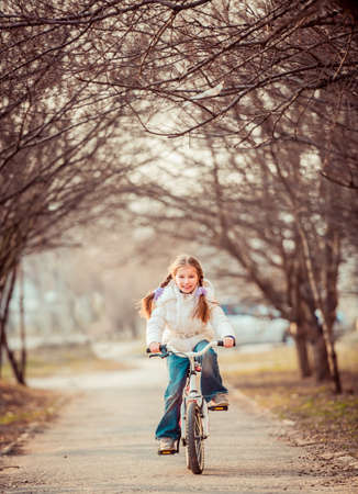 Happy cute little girl riding a bicycle in the springの写真素材