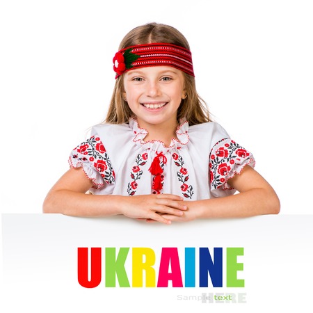happy little girl in the Ukrainian national costume behind white board with space for textの写真素材