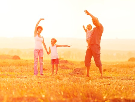 Dad playing with his daughter in a field at sunsetの写真素材