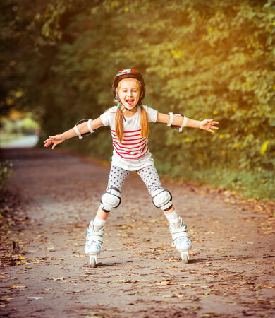 happy little girl on roller skates in the autumn forestの写真素材