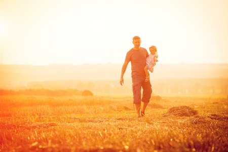 Dad with his daughter in a field at sunsetの写真素材
