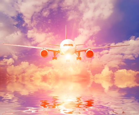 Airplane in the sky at sunsetの写真素材