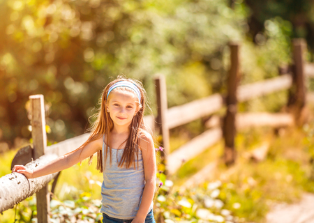 beautiful little girl near a wooden fence in the countrysideの写真素材