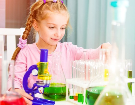 cute little girl with varicolored flasks for chemistryの写真素材