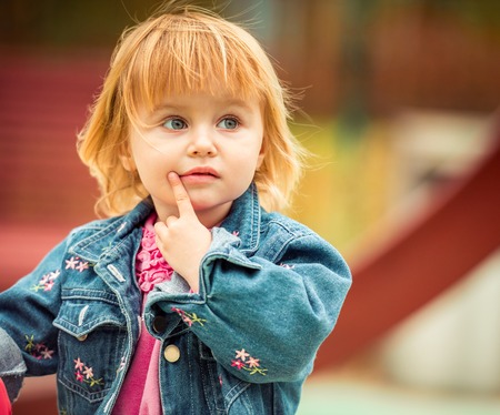 little cute girl playing at the playground in autumnの写真素材