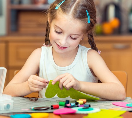 happy cute little girl is engaged in sewing homeの写真素材