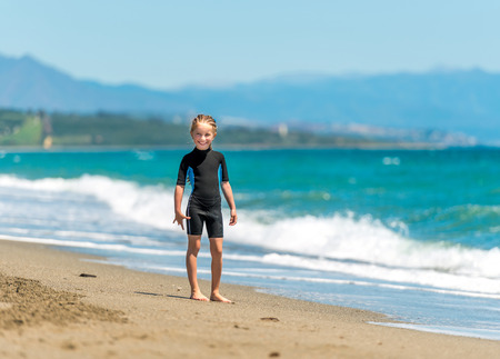 happy little girl in a wetsuit  on the coast.の写真素材