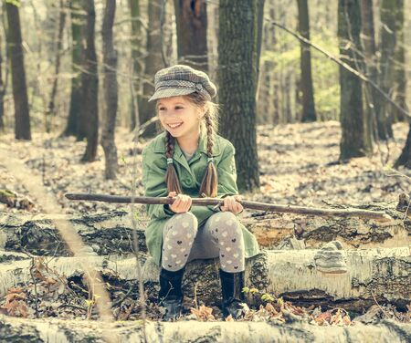 little girl in the woods sitting on a stump. vintage styleの写真素材