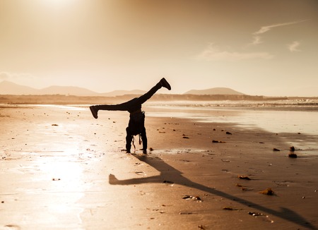 little gymnast silhouette on the beach at sunsetの写真素材